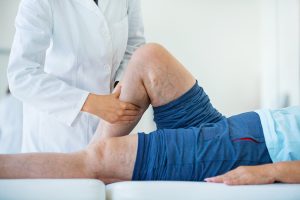 Untersuchung des rechten Beines eines liegenden Patienten auf Gefäßerkrankungen